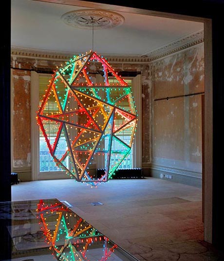 Photo showing wooden framework lined with coloured lights suspended from drawing room ceiling.