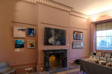 Photo of dining room south wall showing fireplace and seven paintings hanging