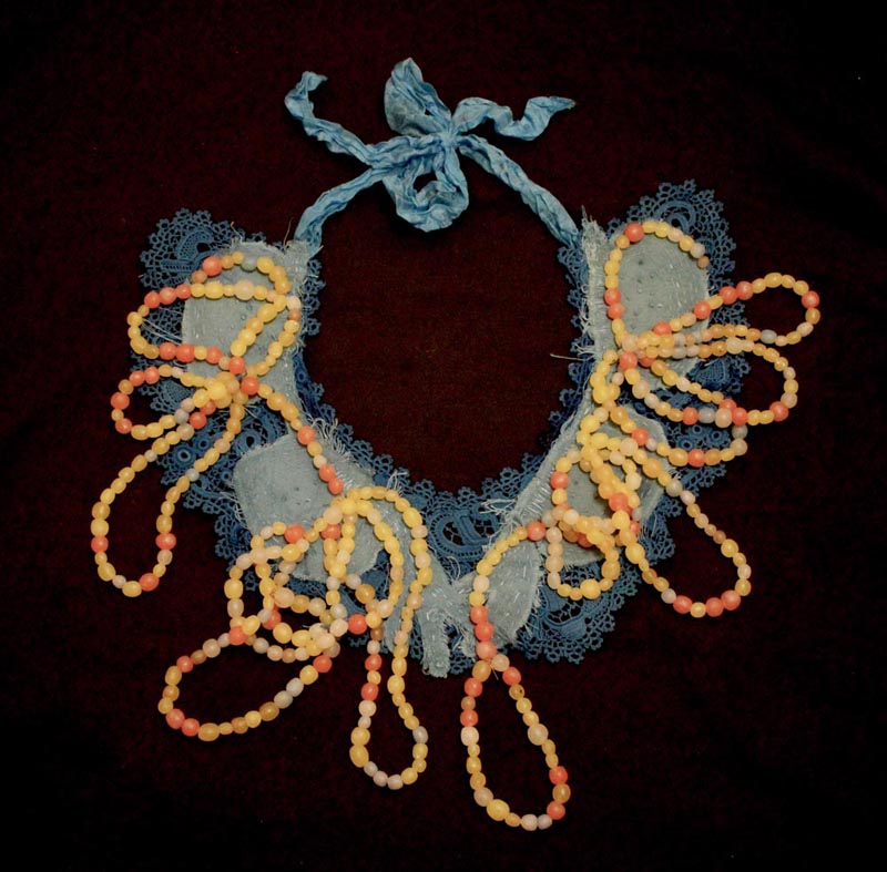Necklace of yellow and amber beads placed on a collar of blue lacework