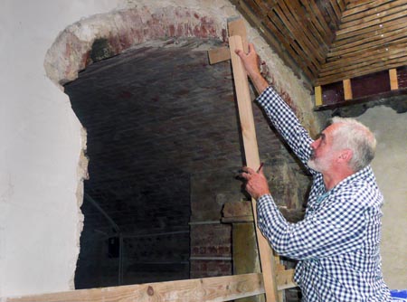 Man holding a plaster trammel against the face of a cellar arch