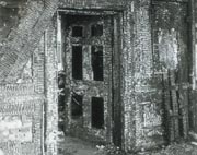 Photograph showing wall and doorway charred and badly damaged by fire 