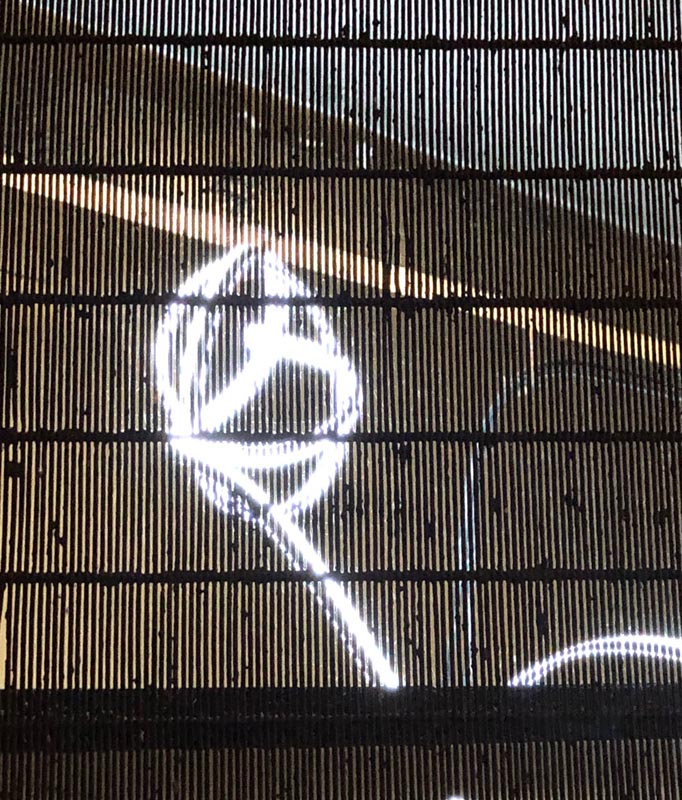 Artwork comprising a glowing white abstract shape seen through a dark vertical grating