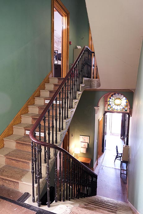 Photo of interior of a Regency house showing a flight of stairs up to a half-landing and a further flight to the next floor level.