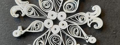 Photo of quilling, white paper on a dark background