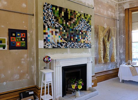 View of drawing room, including white marble fireplace, and showing textile artworks on the wall.