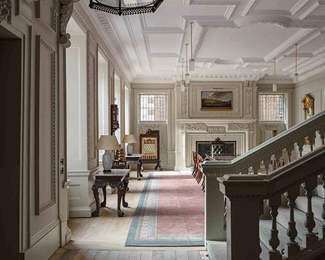 Photo of interior, with ornate fireplace and decorative plasterwork to the ceiling, walls and window surrounds. 