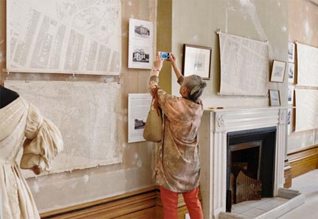 Photo of a visitor taking a photo of one of the exhibits hanging on the wall.