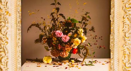 Photo of a flower arrangement contained within an ornate cream and gold frame 