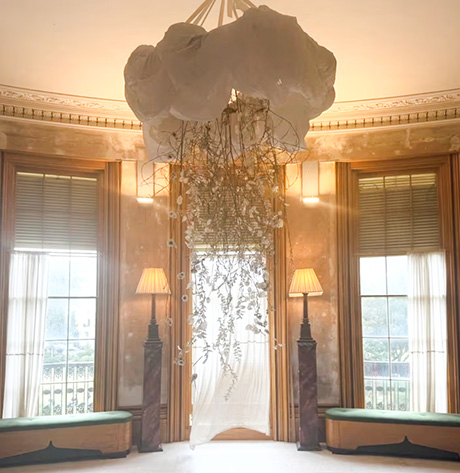 Photo of the drawing room, with a floral arrangement hanging from the ceiling and three windows in the background