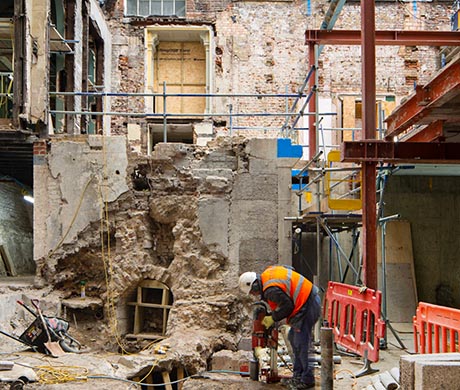 Photo of site with demolished walls, new steel supports and a worker in a hi-viz jacket